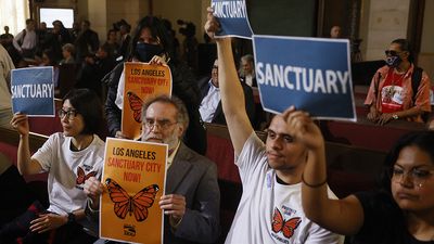 People in the audience hold up signs in support of immigrants as the Los Angeles City Council considers a "sanctuary city" ordinance during a meeting at City Hall in Los Angeles, California, on November 19, 2024. (Immigration law, migrant, US politics, protest)