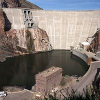 A photo of the Theodore Roosevelt Dam in Arizona, a curved concrete structure built to irrigate desert land by impounding the Salt River.