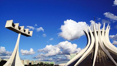 Cathedral of Brasilia, Brazil, designed by Oscar Niemeyer, built in the shape of a crown of thorns. Its bell tower is at the left.