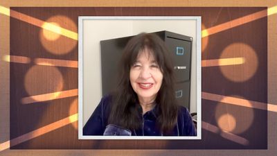 A photo of Joy Harjo, a woman with long dark hair, framed by a stylized border with a wood grain and light streaks.
