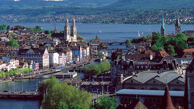 The twin spires of the Grossmunster are a distinctive feature of Zurich's cityscape: the popular panoramic view shows Zurich Downtown Switzerland, with Lake Zurich and the snow-capped Alps in the background.
